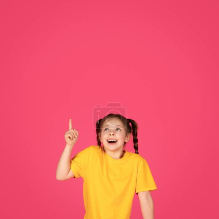 Photo for Interesting Offer. Cute Little Girl Pointing Up At Copy Space Above Her Head With Hand, Preteen Female Child Demonstrating Empty Place For Your Design Or Advertisement Over Pink Background - Royalty Free Image