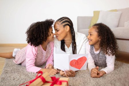 Photo for Celebrating Mothers Day. African American Mom Holding Greeting Card Receiving Gifts From Her Preteen Daughters At Cozy Home Interior. Family Happiness And Holiday Celebration - Royalty Free Image