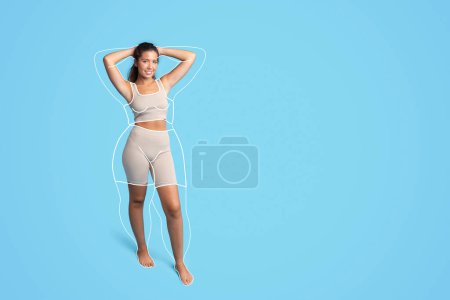 Téléchargez les photos : Joyeux joli millénium caucasien mince athlète femme en vêtements de sport avec corps gras abstrait autour, isolé sur fond de studio bleu. Résultats de perte de poids et de soins corporels, avant et après - en image libre de droit