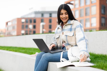 Photo for Cheerful hispanic student lady doing homework or preparing for test outdoors, learning with laptop and copybook, copy space. Studentship and modern education concept - Royalty Free Image