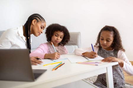 Photo for E-Learning. Two Black Schoolgirls Learning At Laptop, Having Lessons With A Tutor At Cozy Domestic Interior. Mother Helping Her Kids With Distance Study And Homework Routine. Home Schooling Concept - Royalty Free Image