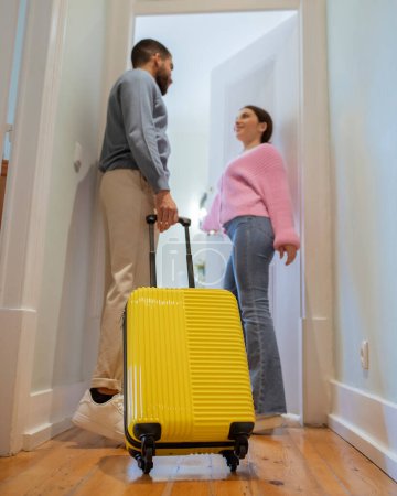 Photo for Hotel Accomodation. Multicultural Tourists Couple With Yellow Travel Suitcase Entering Their Suite, Standing In Doorway Indoors. Full Length, Vertical Shot. Selective Focus On Luggage Bag - Royalty Free Image