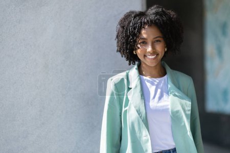 Photo for Traineeship, internship for young professionals concept. Happy pretty curly young black woman in nice formal outfit employee posing outdoor next to office building, smiling at camera, copy space - Royalty Free Image