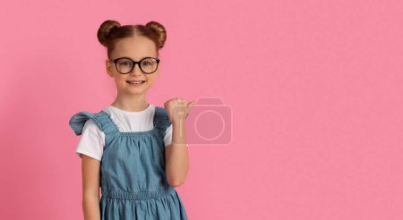 Photo for Look There. Cute Little Girl Pointing Aside At Copy Space With Thumb Up While Standing Over Pink Studio Background, Happy Preteen Female Child Demonstrating Free Place For Design Or Offer - Royalty Free Image