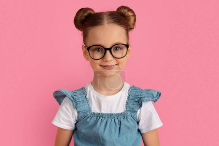 Photo for Portrait of cheerful little girl wearing eyeglasses posing over pink background, joyful preteen female child in stylish eyewear and bun hairstyle smiling and looking at camera, copy space - Royalty Free Image