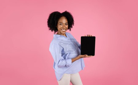 Photo for Glad millennial african american curly pregnant woman with belly show tablet with blank screen, isolated on pink studio background. Website, blog of future motherhood, app for expect baby - Royalty Free Image