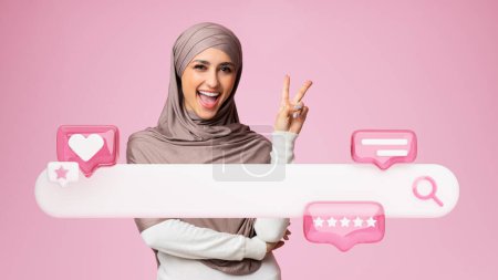 Téléchargez les photos : Meilleur service en ligne. Femme Moyen-Orient positif dans le hijab gesticulant signe de victoire près de l'icône de barre de recherche Internet, avec comme et cinq étoiles messages sur fond rose. Collage, Panorama - en image libre de droit