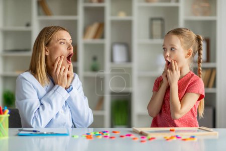 Photo for Speech Therapist Woman Making Articulation Exercises With Little Girl At Therapy Session, Cute Preteen Female Child Working On Pronunciation With Logopedist Lady During Meeting In Office - Royalty Free Image