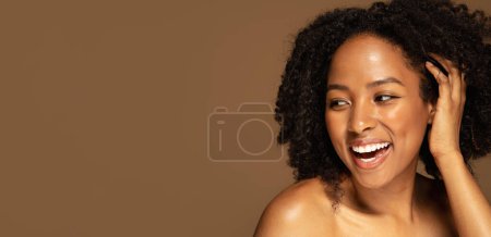 Foto de Abraza tu piel, aceptación, amor por tu propio cuerpo. Sensual hermosa mujer negra medio desnuda tocando su cabello tupido, riendo y mirando el espacio de copia. aislado en el fondo del estudio, banner web - Imagen libre de derechos