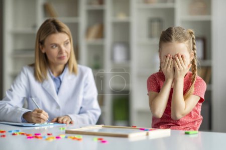 Photo for Kids Mental Health. Upset Little Girl Crying During Meeting With Psychotherapist, Depressed Female Child Covering Face With Hands And Sobbing, Suffering Nervous Breakdown, Closeup Shot - Royalty Free Image