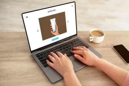 Photo for Lady sitting at table and using modern laptop with cream jar on screen, woman shopaholic enjoy ordering beauty care cosmetics, buying at online store - Royalty Free Image