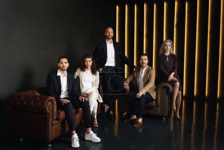Téléchargez les photos : Direction de l'entreprise. Groupe de cinq hommes d'affaires du Moyen-Orient confiants dans des tenues formelles assis dans l'intérieur de bureau de luxe noir. Concept de carrière et de réussite professionnelle - en image libre de droit