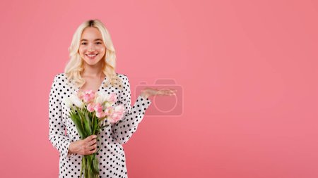 Foto de Preciosa mujer europea sosteniendo montón de tulipanes celebrando Mujer, s Día o cumpleaños, la publicidad de su producto en el fondo del estudio rosa, maqueta, panorama con espacio libre - Imagen libre de derechos