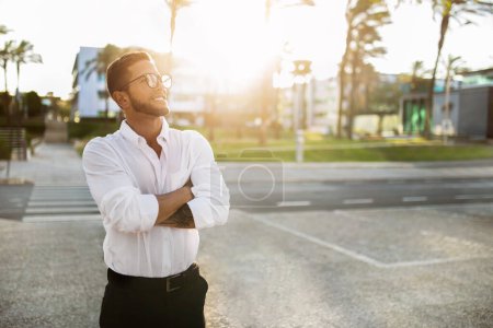 Photo for Happy dreamy european businessman in formal wear standing outdoors with folded arms and looking away at empty space. Successful entrepreneur man posing outside - Royalty Free Image