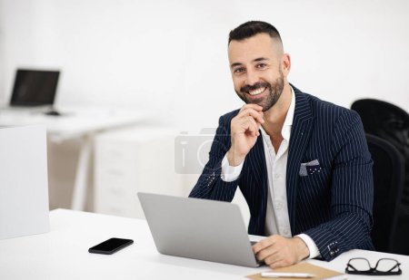 Photo for Happy european adult man in suit with beard working on laptop in office coworking interior. Successful business remotely with technology, boss and startup, marketing project, ad and offer - Royalty Free Image