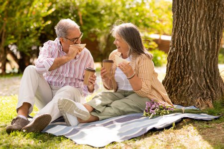 Photo for Cheerful old caucasian husband and wife eat sandwich and drink tea, enjoy picnic, lunch together in park, outdoor. Coffee break, romantic date, lifestyle and weekend, free time - Royalty Free Image