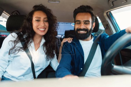 Photo for Excited arab couple enjoying car ride sitting in new automobile inside, spouses driving and testing auto in dealership. Happy middle eastern vehicle buyers - Royalty Free Image