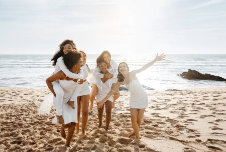 Photo for Female friends piggybacking each other at the beach, enjoying time together, cheerfully smiling and fooling around, free space. Best friends having fun and enjoying their vacation - Royalty Free Image