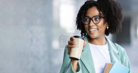 Foto de Primer plano de sonriente hermosa rizada milenaria mujer negra con traje casual inteligente y anteojos beber café al aire libre, empleado tienen descanso para el almuerzo, panorama con espacio para copiar - Imagen libre de derechos