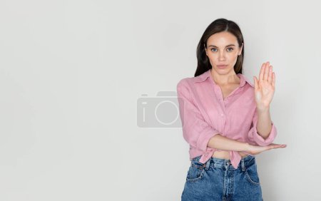 Photo for Portrait of serious young caucasian woman in casual outfit standing with outstretched hand showing stop gesture isolated over white background, copy space. No violence, stop abuse, women rights - Royalty Free Image