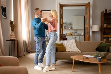 Photo for Full Length Shof Of Happy Senior Couple Enjoying Slow Dance, Celebrating Marriage Anniversary In Cozy Living Room At Home. Spouses Dancing Together, Free Space For Text Advertisement - Royalty Free Image