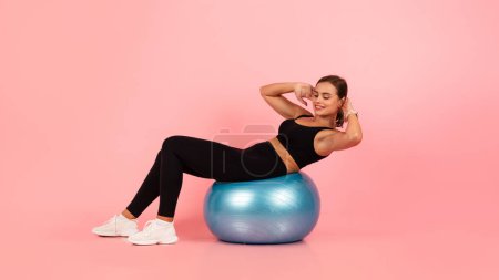 Beautiful Sporty Woman In Activewear Training On Fitness Ball And Smiling, Happy Young Athletic Female Exercising With Swiss Ball Over Pink Studio Background, Panorama With Copy Space