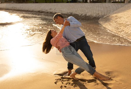 Photo for Happy mature couple dancing on the beach together on sunset time, loving romantic middle aged spouses having fun outdoors, cheerful husband and wife enjoying summer vacation, copy space - Royalty Free Image