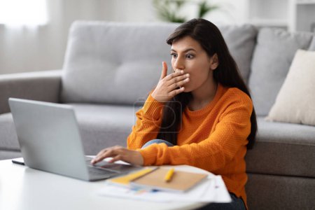 Photo for Bug, error, broken app. Shocked emotional pretty young indian woman looking at laptop screen and cover her mouth, freelancer have difficulties with software, home interior - Royalty Free Image