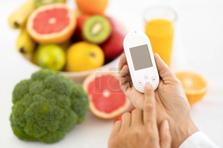 Photo for Adult european lady doctor nutritionist shows glucometer, organic fruits and vegetables in office clinic. Diabetes control, health care, proper nutrition, medical weight loss, diet and treatment - Royalty Free Image