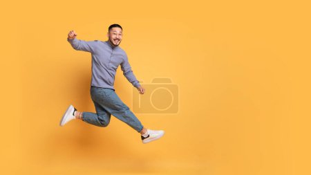 Photo for Hooray. Overjoyed Young Asian Guy Jumping In Air Over Yellow Background In Studio, Happy Cheerful Millennial Man Having Fun, Shouting Yes, Expressing Positive Emotions, Panorama With Copy Space - Royalty Free Image
