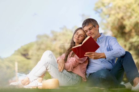 Photo for Romantic mature couple reading books while spending free time together outdoors, happy middle aged husband and wife enjoying summer day in park, aged spouses relaxing on green lawn, copy space - Royalty Free Image