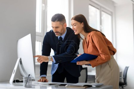 Photo for Successful caucasian man and woman coworkers in formal outfits working with computer, having conversation and discussing new project or startup at office - Royalty Free Image