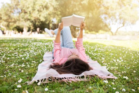 Photo for Middle Aged Lady Reading Book While Lying On Plaid Outdoors In Bloomy Park, Peaceful Mature Female Relaxing On Green Lawn In Summer Time, Reader Woman Enjoying Interesting Novel, Copy Space - Royalty Free Image
