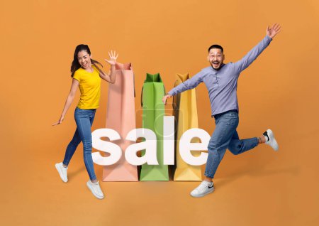 Photo for Discount Offer. Cheerful Asian Family Couple Near Giant Shopping Bags And Word Sale Jumping, Posing And Having Fun On Orange Studio Background. Shopaholics Joy Concept. Collage, Full Length Shot - Royalty Free Image