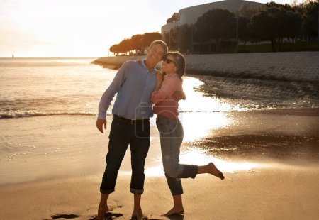 Photo for Outdoor Date. Happy mature couple laughing together and embracing at sandy beach, cheerful middle aged spouses having fun during walk near sea, enjoying spending time with each other, copy space - Royalty Free Image