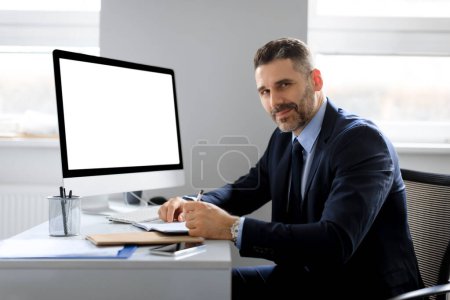Photo for Cheerful european middle aged businessman sitting at workplace with computer with blank screen, free space, mockup template. Business website and startup concept - Royalty Free Image