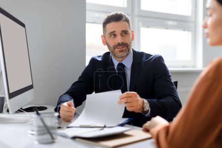 Photo for Employment concept. Businessman having job interview and talking with woman headhunter sitting at desk in office. HR manager reading CV speaking with job applicant - Royalty Free Image