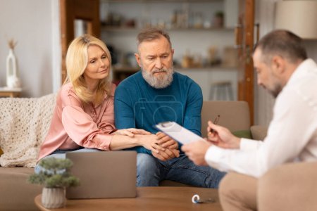 Photo for Consultation With Specialist. Professional Financial Advisor Man Consulting Unhappy Senior Couple Sitting Near Laptop And Showing Business Papers Indoors. Selective Focus - Royalty Free Image