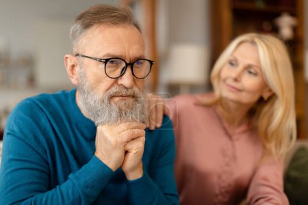 Photo for Attentive senior lady comforting her upset serious husband, touching his shoulder and saying supportive words sitting in living room. Support and trust between partners in marriage. Selective focus - Royalty Free Image