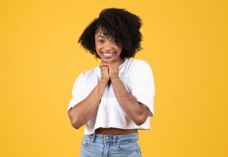 Photo for Glad happy pretty millennial black lady in casual presses hands to chest, rejoices at good news, isolated on orange studio background. Fun, human emotions, sale, win, ad and offer - Royalty Free Image