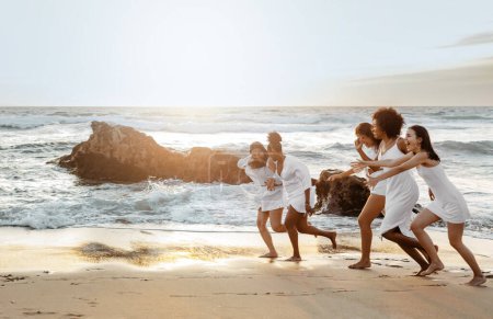Photo for Happy women running along ocean shore while celebrating bachelorette party on the beach, having fun on coastline, full length shot, free space - Royalty Free Image