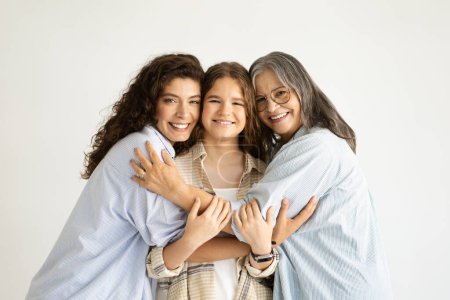 Photo for Glad adult, elderly and teenager women and girl hugging, isolated on white studio background. Family support, female generation, relationships and love at free time at weekend, lifestyle - Royalty Free Image