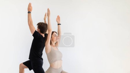 Photo for Positive calm young european lady and guy in sportswear practicing yoga, make breathing exercises with tracker on gray background, panorama. Sport and fitness, workout together, health care - Royalty Free Image