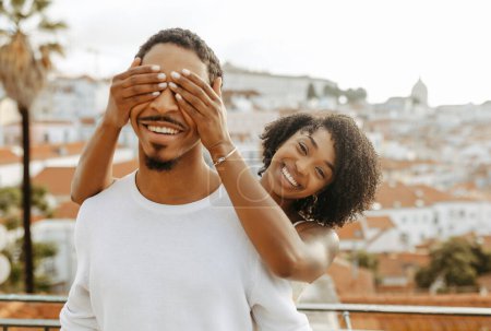 Photo for Happy millennial african american woman close eyes to man, outdoor. Surprise, lifestyle, love relationship and summer travel together, couple enjoy trip, walk and free time and vacation - Royalty Free Image