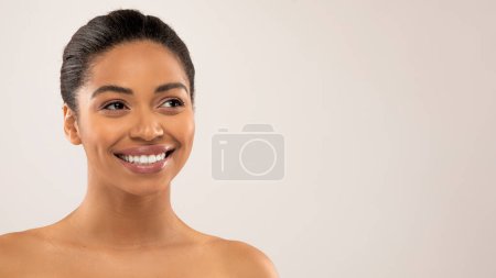 Téléchargez les photos : Médecine esthétique, concept de cosmétologie moderne. Portrait de jolie femme afro-américaine millénaire souriante et topless regardant l'espace de copie, isolée sur fond gris, bannière web - en image libre de droit