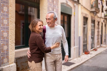 Téléchargez les photos : Destination de voyage. Couple de retraités européens souriants embrassant debout dehors sur la belle rue de Lisbonne. Homme et femme mûrs jouissant de vacances et d'une vie active à la retraite en Europe. Espace vide - en image libre de droit