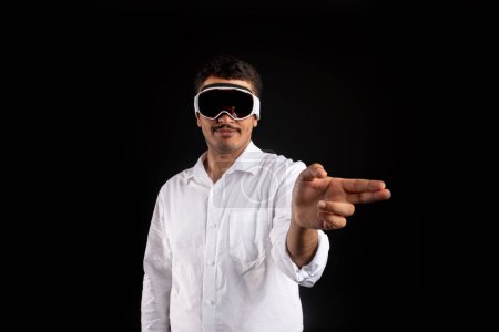 Téléchargez les photos : Homme d'affaires portant de nouvelles lunettes de vision pro VR, touchant un écran virtuel ou des objets par les doigts, interagissant avec le cyberespace. Homme moderne en réalité virtuelle lunettes de jeu vidéo en ligne - en image libre de droit