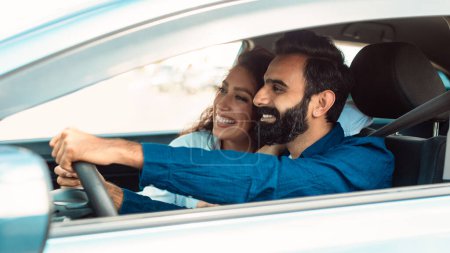 Foto de Alegre pareja árabe conducir su nuevo coche y explorar las carreteras, sentado con la ventana abierta, el hombre detrás del volante y su esposa celebrando la compra de vehículos nuevos - Imagen libre de derechos