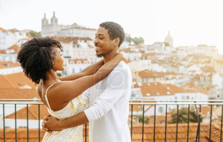 Photo for Smiling young african american guy hugging woman in dress, enjoy romantic date and travel vacations, outdoor. Love relationships, holiday and spare time, honeymoon in city together - Royalty Free Image