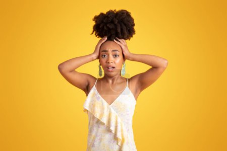 Photo for Scared frightened sad confused young black woman with open mouth holding head with hands, isolated on yellow background, studio. Stress, pressure, what have I done, bad news, emotions, ad and offer - Royalty Free Image